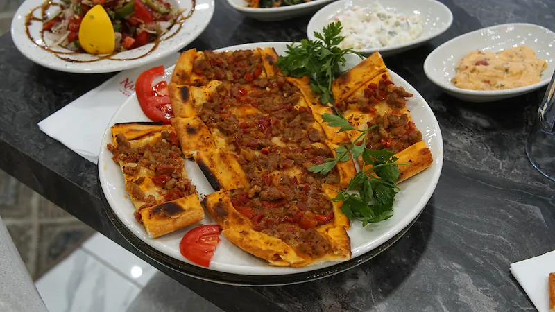 Dilimlenmiş etli pide, maydanoz ve domatesle