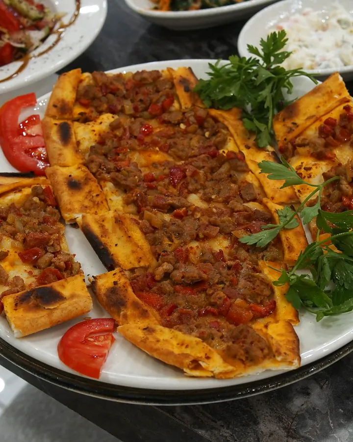 Dilimlenmiş kıymalı pide, maydanoz ve domates